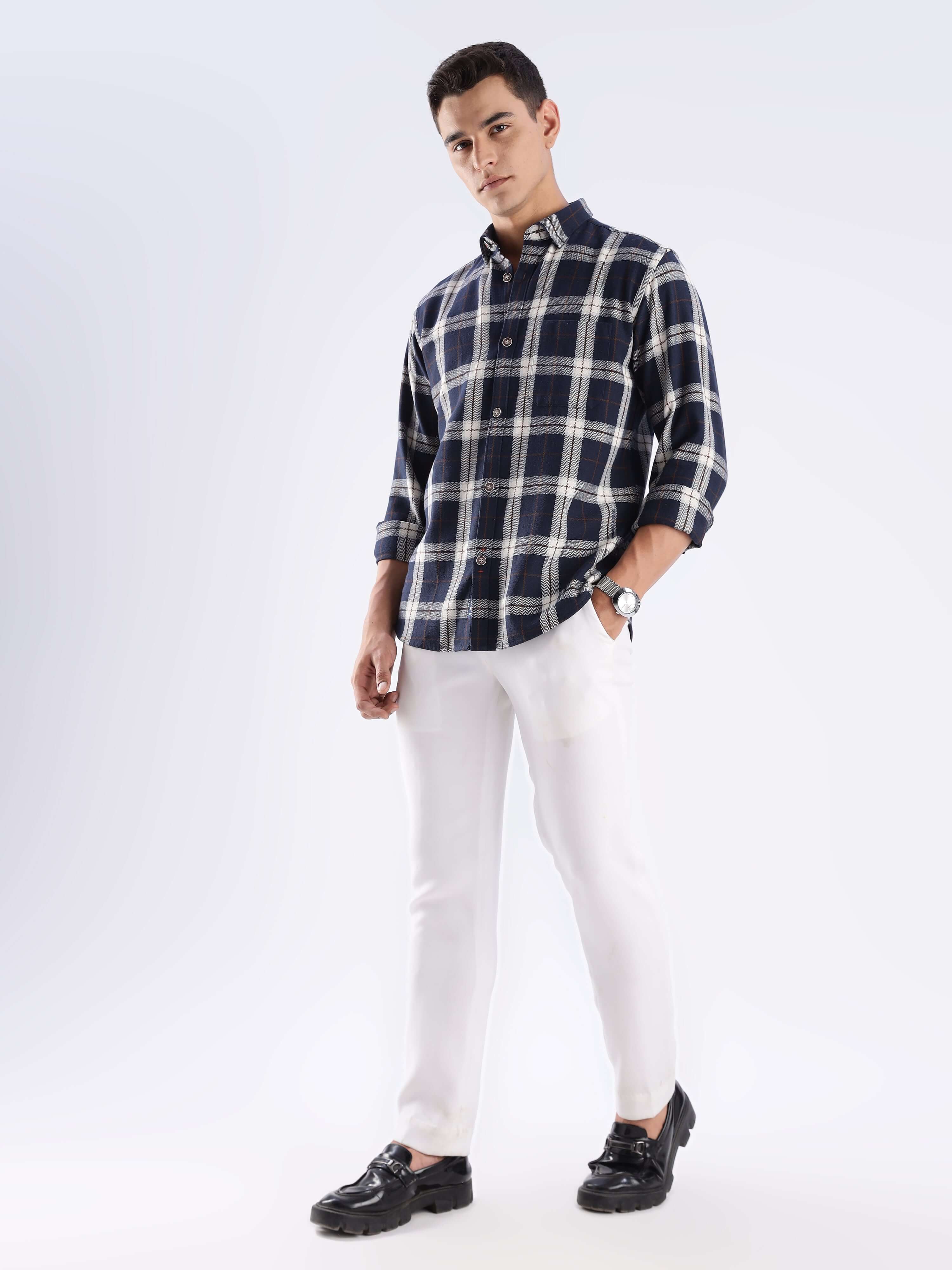 Model wearing a blue checked recycled cotton shirt styled with white pants and black shoes, showcasing sustainable fashion.