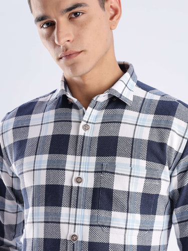 Man wearing a checked shirt made from recycled cotton, featuring blue and white patterns, stylish and sustainable fashion.
