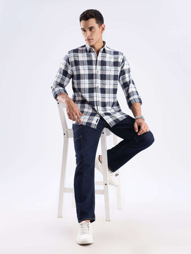 Model wearing a blue and white checked recycled cotton shirt with dark jeans, showcasing sustainable fashion.
