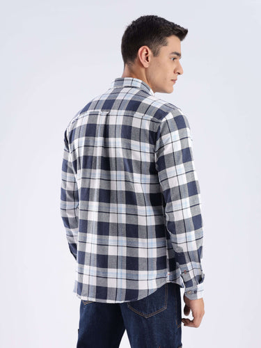 Man wearing a blue checkered recycled cotton shirt, showcasing sustainable fashion and durability.