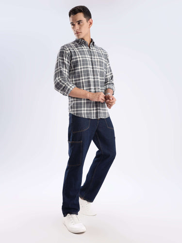 Man wearing a stylish checked shirt made of recycled cotton, paired with dark jeans and white sneakers.