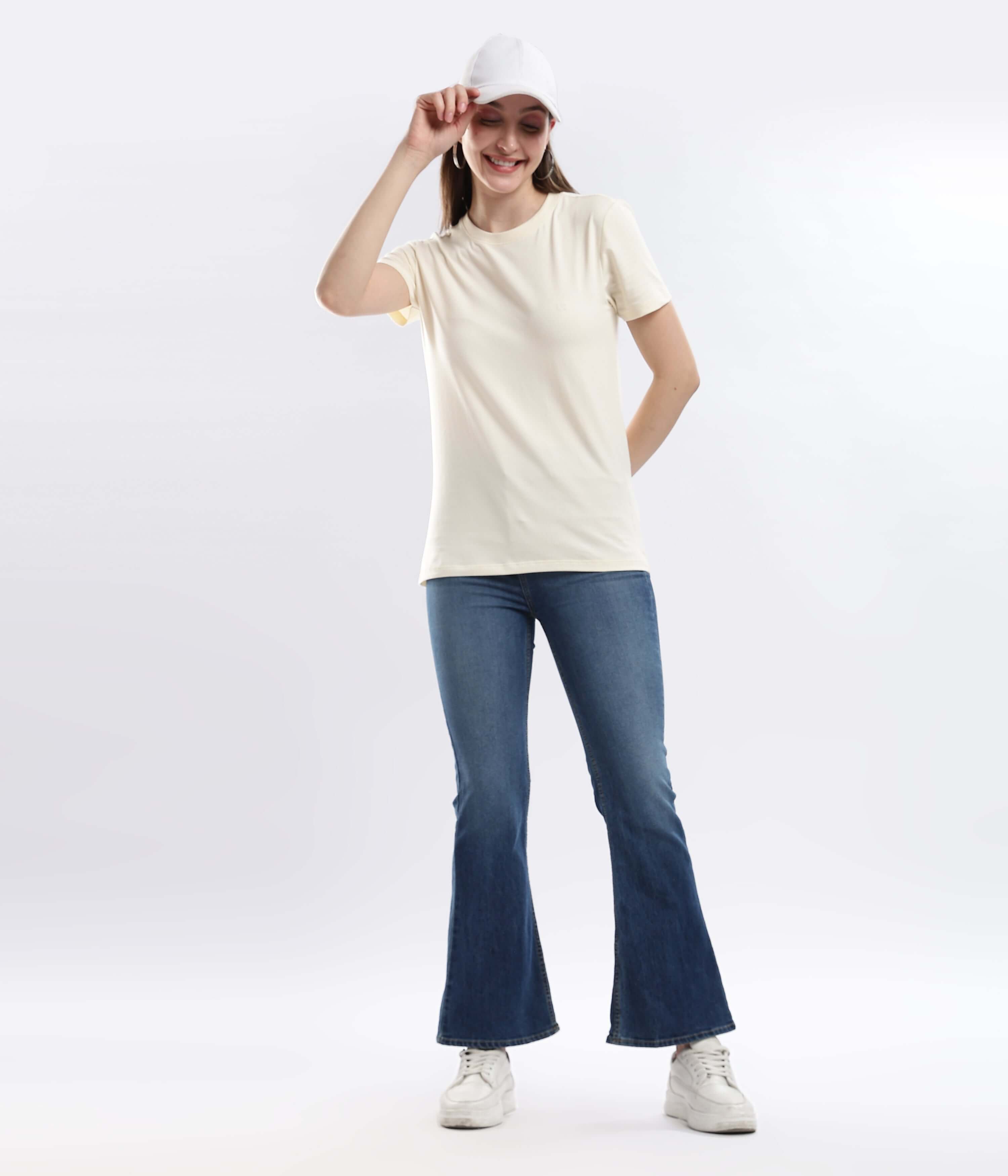 Model wearing Polar Off-white t-shirt with blue jeans and a cap, showcasing style and comfort in everyday fashion.