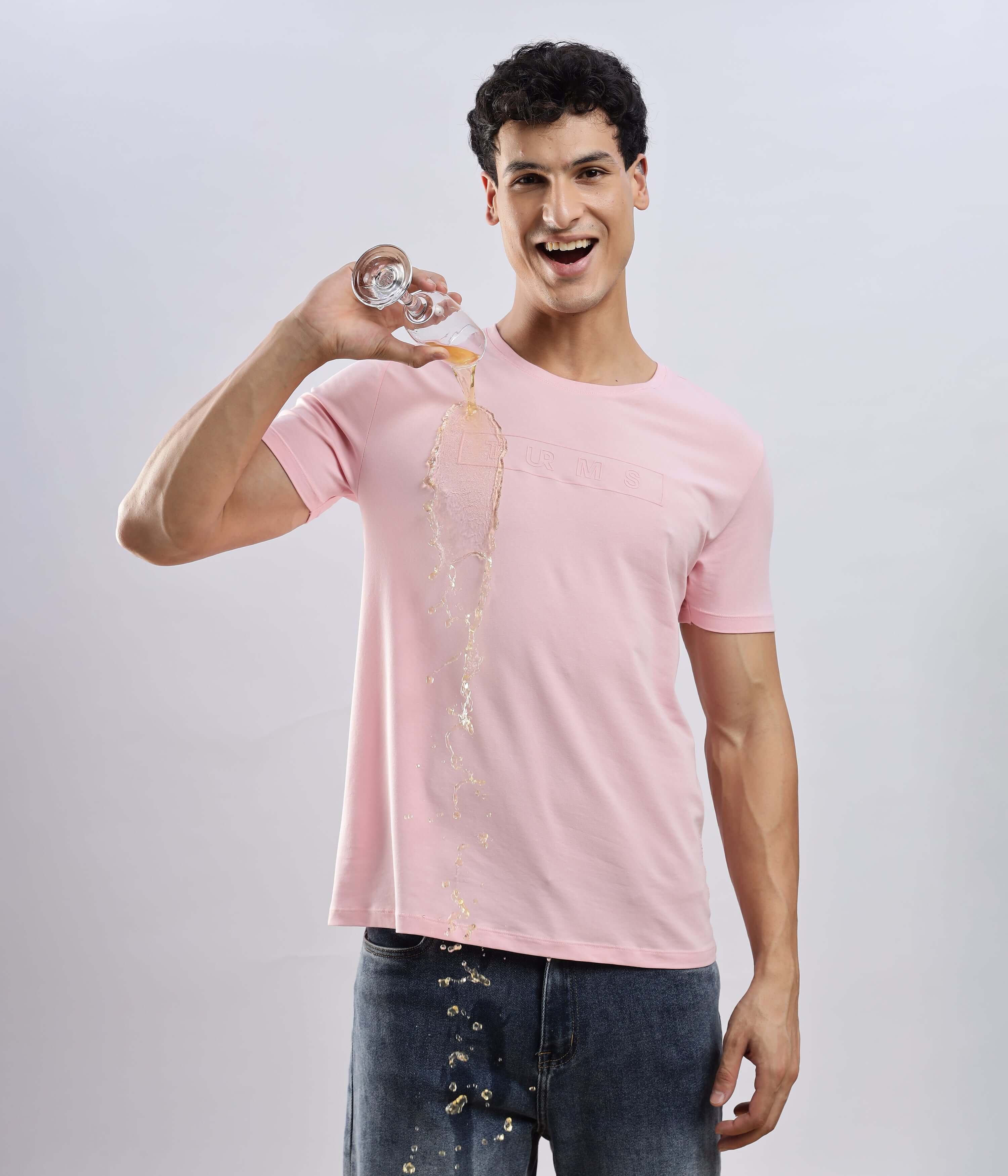 Man wearing Quartz Pink cotton tshirt demonstrating its waterproof features, showcasing style and functionality.