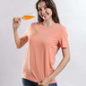 Model wearing Womens casual t-shirt Ember Orange cotton t-shirt demonstrating waterproof feature while pouring liquid from a glass.