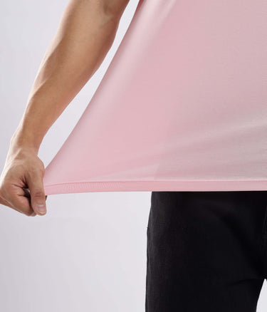 Close-up of a person holding the hem of a Quartz Pink cotton t-shirt, showcasing its stretchable and soft fabric.