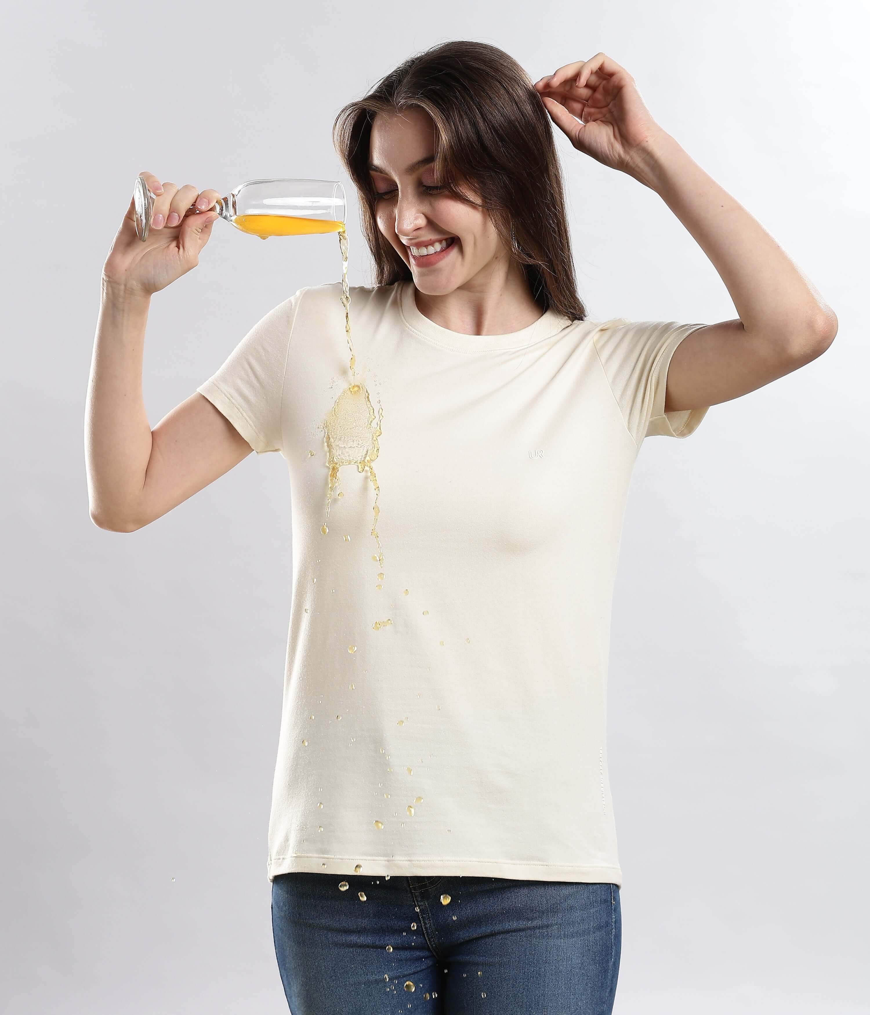 Woman wearing Polar Off-white cotton t-shirt, demonstrating water resistance while spilling a drink.