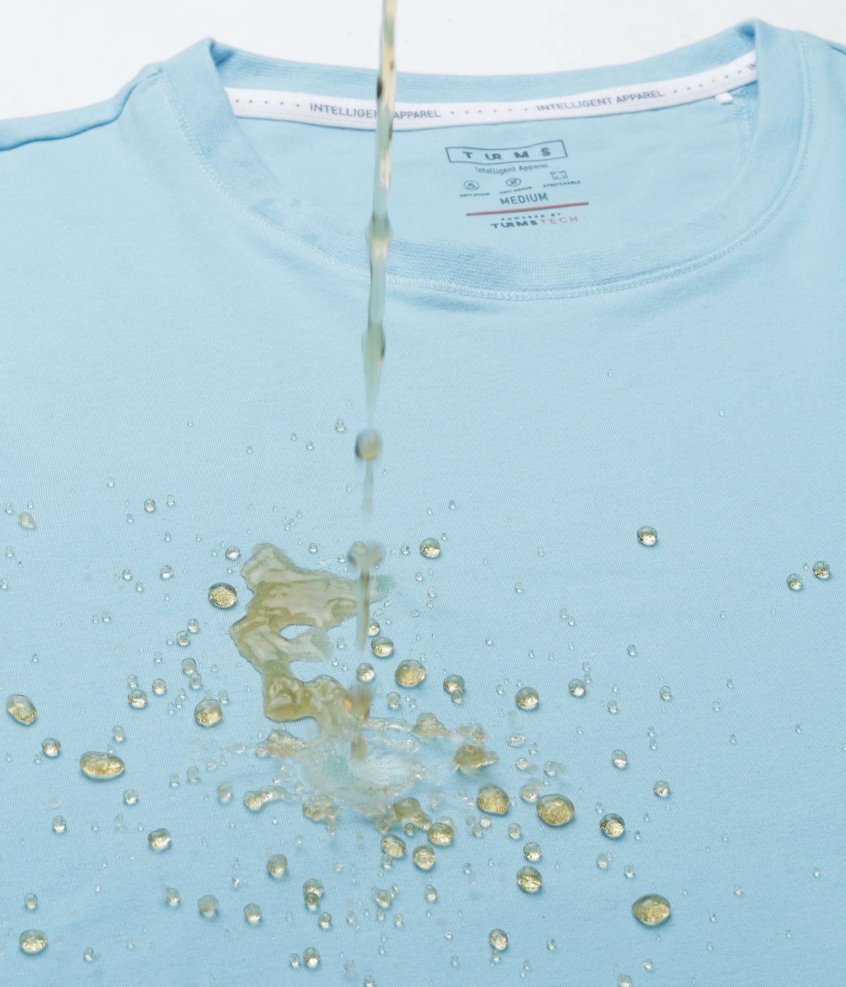 Alaskan Blue Turms Intelligent Apparel t-shirt with water droplets showcasing its water-resistant feature.