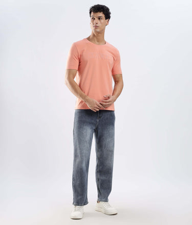 Man wearing Ember Orange Turms Worry-Free Intelligent T-Shirt with jeans, showcasing style and comfort.