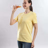Woman wearing Womens casual t-shirt Aura Yellow cotton tshirt, demonstrating its waterproof feature while enjoying a drink.