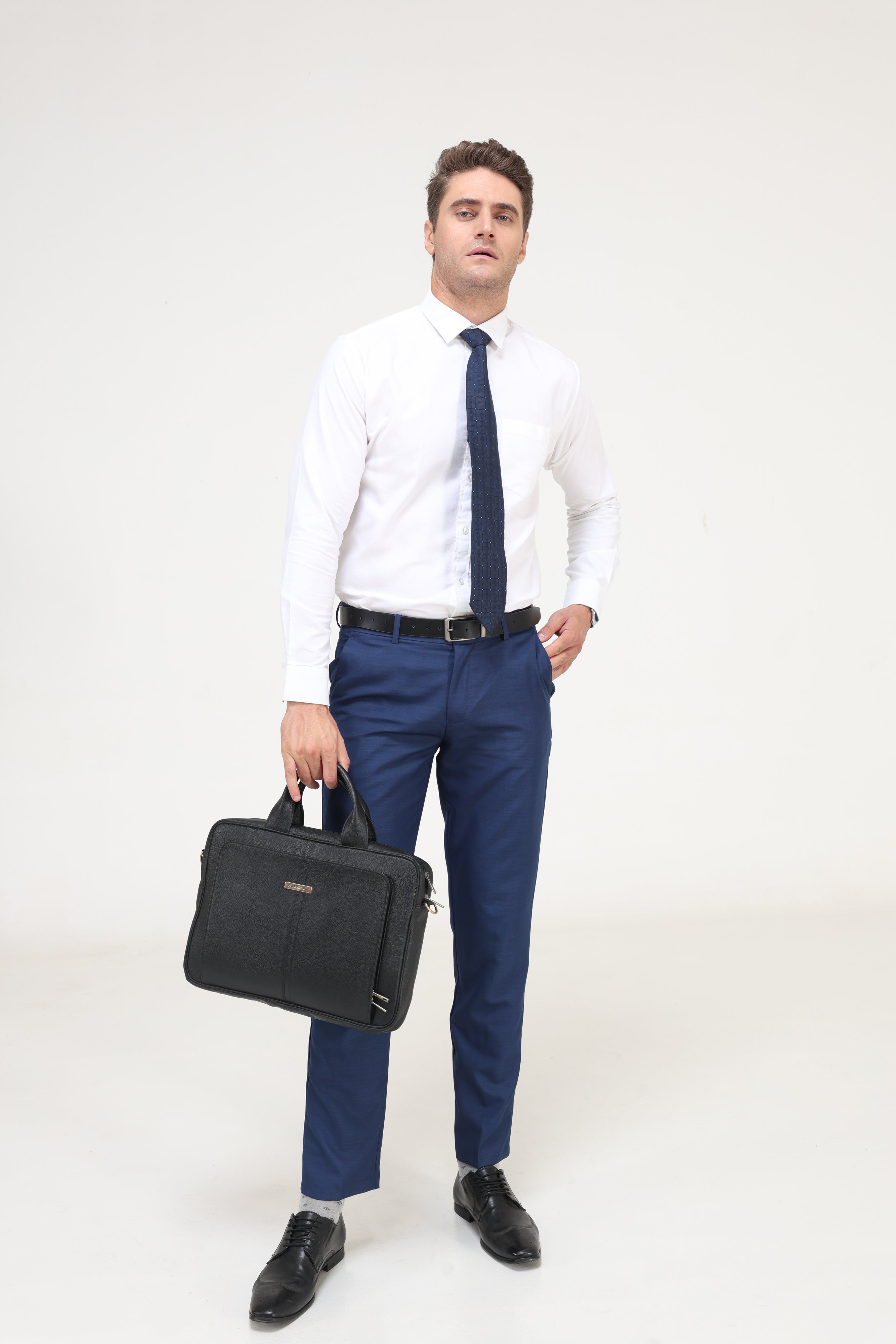 Man wearing Moonlite White Oxford shirt and blue trousers, holding a black briefcase. Stylish menswear, premium white shirts, branded shirts for men.