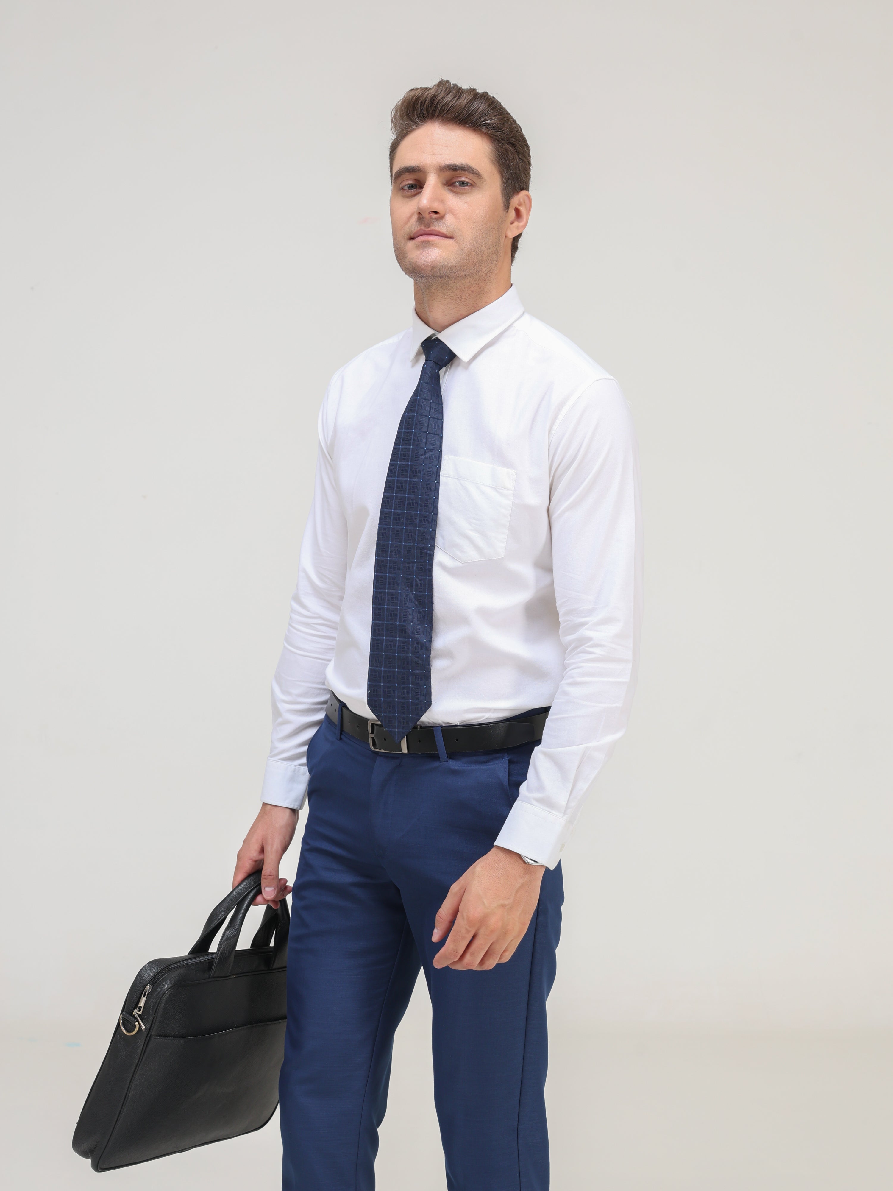 Man wearing Moonlite White Oxford Turms shirt, paired with blue trousers and a tie, carrying a black briefcase - best shirts for men.