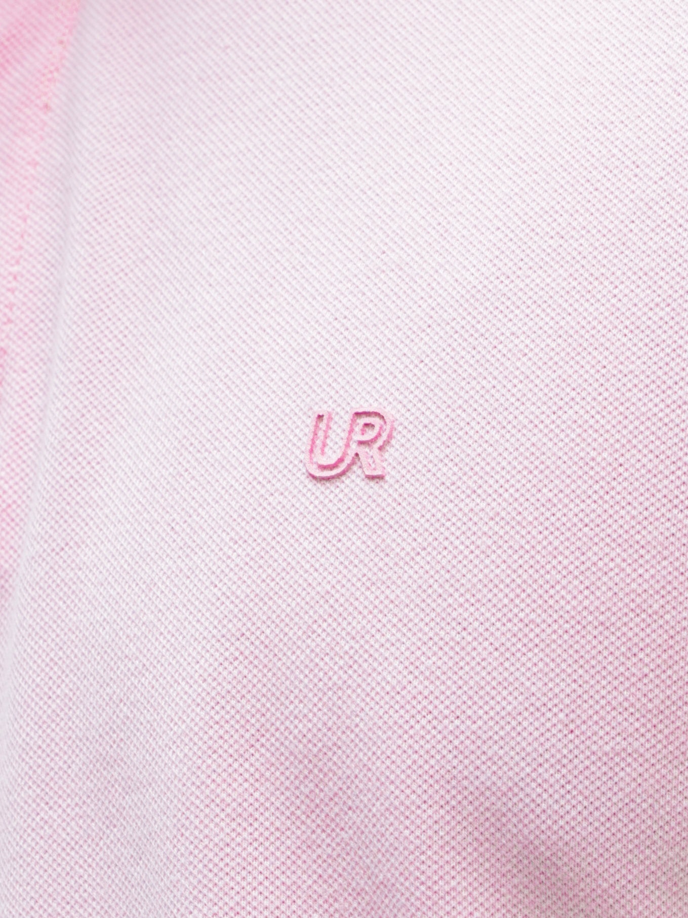 Light pink Turms Polo t-shirt close-up showing the "UR" logo embroidery, featuring premium cotton and spandex fabric with anti-stain and anti-odor properties.