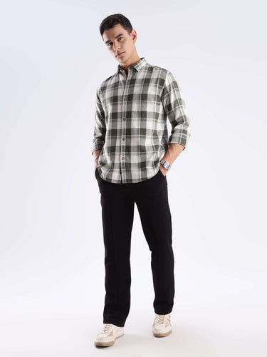 Man wearing a stylish checked shirt made from recycled cotton, paired with black pants and sneakers, showcasing sustainable fashion.