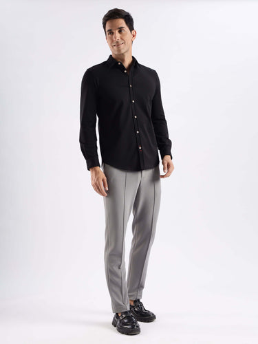 Man wearing a Venice Black knitted shirt and grey trousers, featuring 8-way stretch and anti-odour technology.