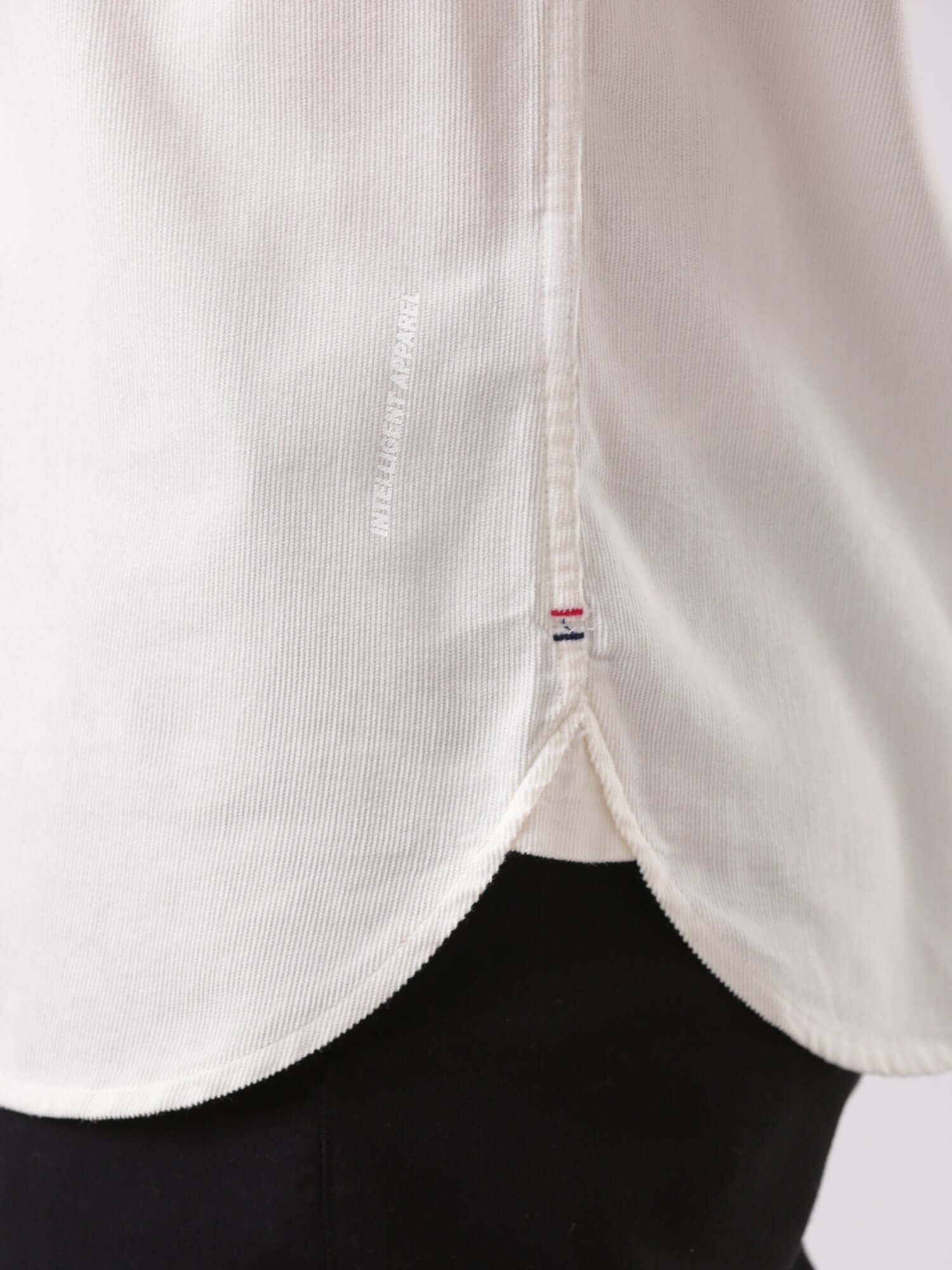 Detail view of the White Grizzly corduroy shirt showcasing the elegant hem and stitching quality.